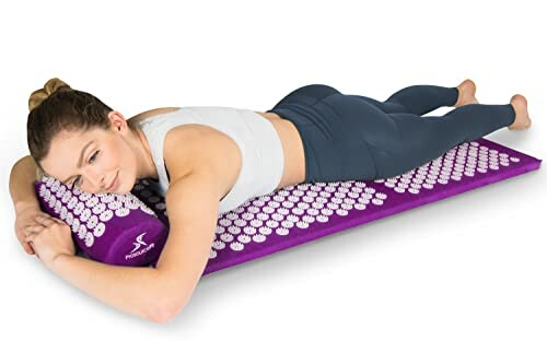 Woman lying on a purple acupressure mat.